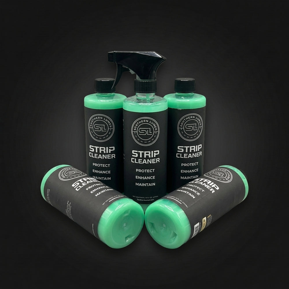 Five bottles of Strip Cleaner grouped on a dark background, three standing and two lying on their sides