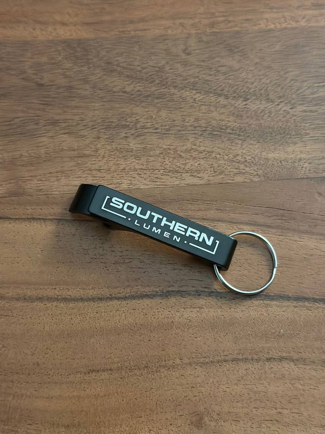 Southern Lumen branded bottle opener with a sleek black finish, featuring the Southern Lumen logo engraved, perfect for everyday use.