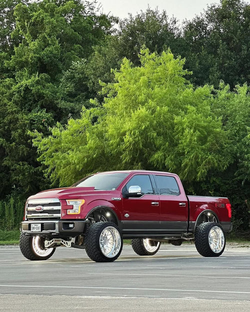 Dual chip switchback wheel lights in white running light mode on a lifted red F-150 parked on pavement in daylight
