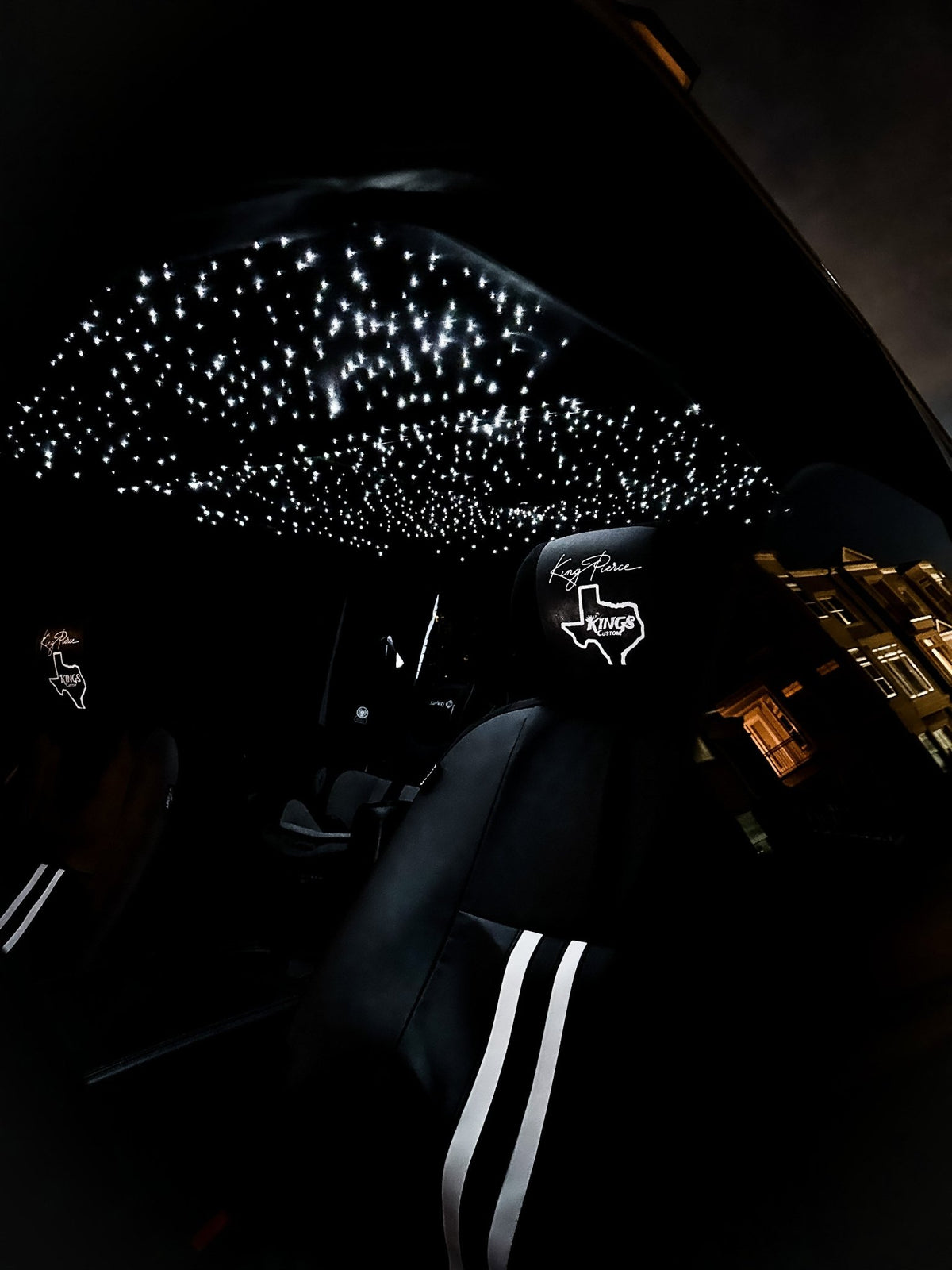 Starlight headliner lit white inside a truck cab at night, fiber optic stars glowing above the black seats